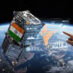 A satellite with the Indian flag orbits above the Earth, positioned over India. A holographic interface with data visualizations, a map of India, and the logos of ISRO and Tata Elxsi floats in front of it, while a hand points to a specific data point.