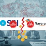 A detailed graphic representing the halting of financial transactions. The central image shows a broken red lightning bolt separating the logos of SBI and Nayara Energy, both of which are overlaid with a red circle 'NO ENTRY' symbol. Gold currency coins are falling from the break. The top half of the image features a stylized, light blue world map with red borders and blurred silhouettes of people. The bottom half shows a gavel and a document labeled 'SANCTIONS' on a table, with the blurred figures of people in the background.